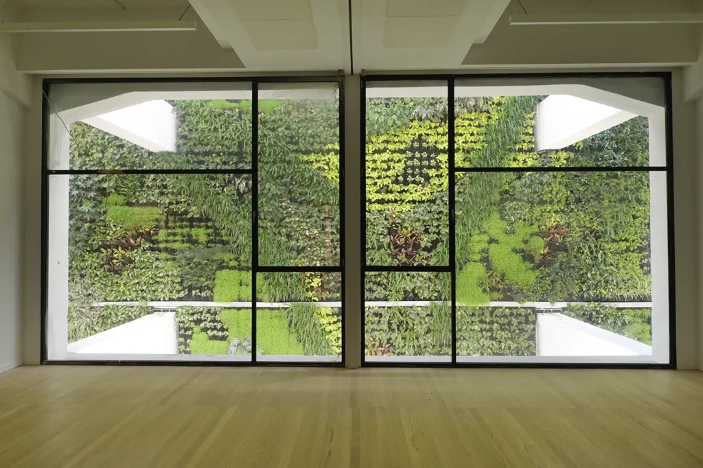 Cristalera de una sala a través de la cual se ve un jardín verde vertical